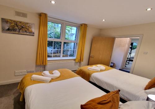 two beds in a room with yellow curtains at The Kenilworth Spacious 2-bedroom w/ Free Parking by Sublime Stays in Spon End