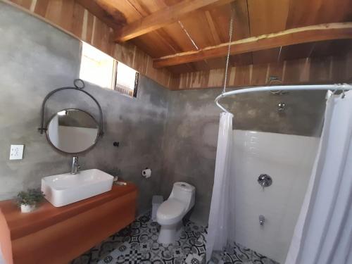 uma casa de banho com um lavatório, um WC e um espelho. em Cabaña Tribu 