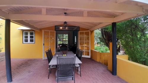 a covered patio with a table and chairs at Landhuis Bona Vista in Willemstad