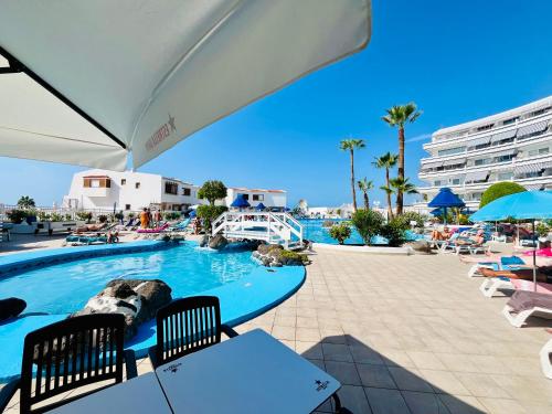 una piscina in un resort con sedie e ombrelloni di Angel's house at Club Atlantis ad Adeje