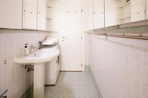 a white bathroom with a sink and white cabinets at Bilocale Bocconi - silenzioso - piano alto in Milan