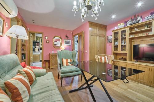 un salon avec des murs roses et une table en verre dans l'établissement Apartamentos Carlos, à Madrid