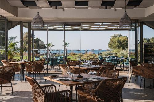 Myrion Beach Resort & Spa - Adults Only في ييراني: مطعم بطاولات وكراسي ونوافذ كبيرة