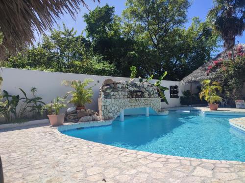 uma piscina com um banco ao lado de uma parede em Ltu Garden em Negril