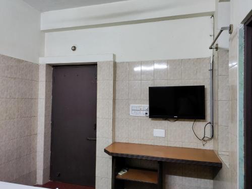 Zimmer mit einem TV an einer Wand mit einer Tür in der Unterkunft Jeyanthi Tower Vellore in Vellore