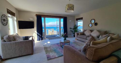 a living room with couches and a view of the ocean at The BoatHouse in Sconser