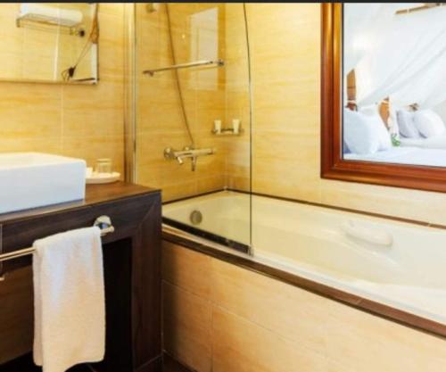 bagno con vasca, lavandino e specchio di Domina coral bay elisir SPA a Sharm El Sheikh