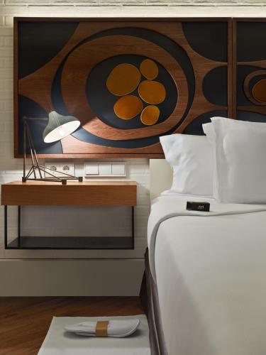 a bedroom with a bed with a desk and a painting at H10 Metropolitan 4* Sup in Barcelona