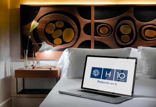a laptop computer sitting on top of a bed at H10 Metropolitan 4* Sup in Barcelona