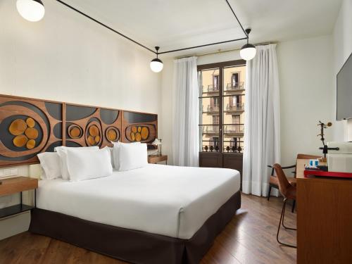 a bedroom with a large white bed and a desk at H10 Metropolitan 4* Sup in Barcelona