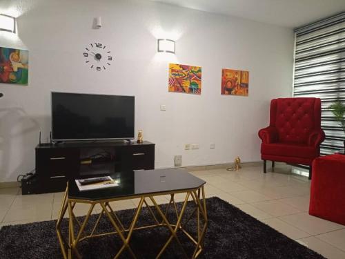 - un salon avec une télévision et une chaise rouge dans l'établissement 2 bedroom apartment at 1004 Estate, à Lagos