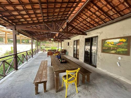 d'une terrasse avec une table en bois et des chaises jaunes. dans l'établissement Pousada Monte Flor Guaramiranga CE, à Guaramiranga