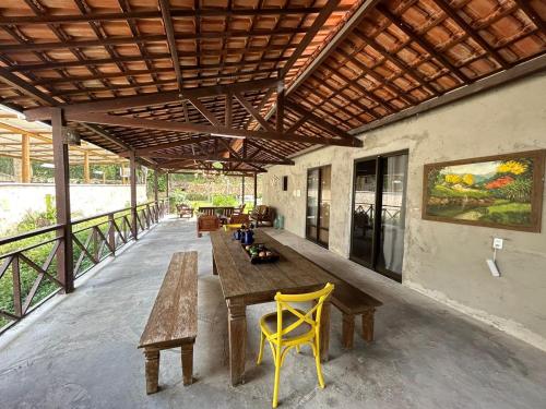 a patio with a wooden table and yellow chairs at Pousada Monte Flor Guaramiranga CE in Guaramiranga