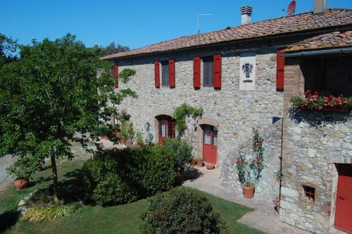 a stone building with red doors and flowers on it at Agriturismo San Ansanino- Piscina con spiaggia-Aria condizionata in Pari