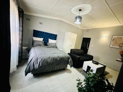 una camera con letto con testiera blu e sedia di The Curve Apartments Unit 16 a Johannesburg