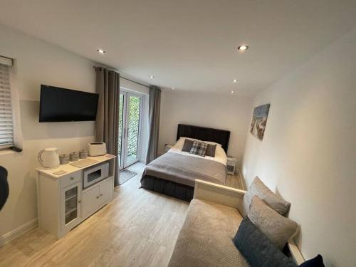 a bedroom with a bed and a couch at Modern stylish studio flat near Leigh on sea. in Hadleigh