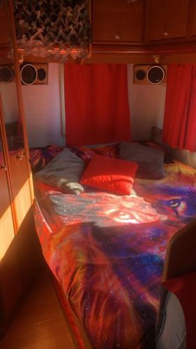 a bed in a room with a colorful comforter at Camping car fixe dans la campagne in Pianottoli-Caldarello