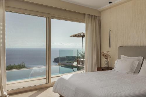 a bedroom with a bed and a view of the ocean at Apolis Villas & Suites Resort in Parga