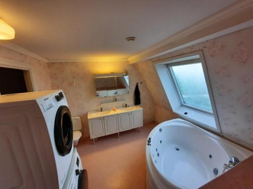uma casa de banho com uma banheira, um lavatório e uma janela em Semester Hem 2 Storvik em Storvik