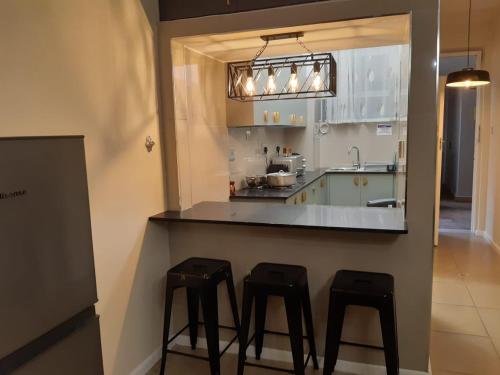 a kitchen with three black stools at a counter at Durban Beachfront OceanSeaside Self Catering Apartments in Durban