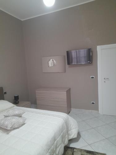 a white bedroom with a bed and a television on the wall at Casa Brezza marina in Barletta