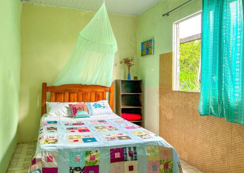 a bedroom with a bed with a comforter and a window at Otima casa proxima a praia do Acuipe em Ilheus BA in Ilhéus