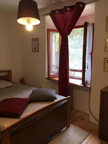 a bedroom with a bed with a red curtain and a window at B&B Il Mulino alla Busa in Vallarsa