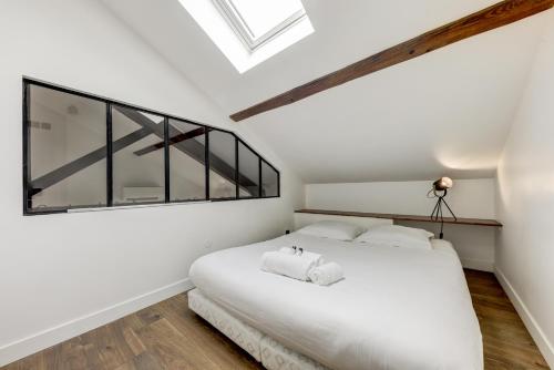 a bedroom with a white bed and a large window at L'Industrie-Loft-T2-Clim-Parking à proximité in Pierre-Bénite