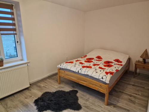 een slaapkamer met een bed met rode bloemen erop bij Przestronny apartament +siłownia in Bytom