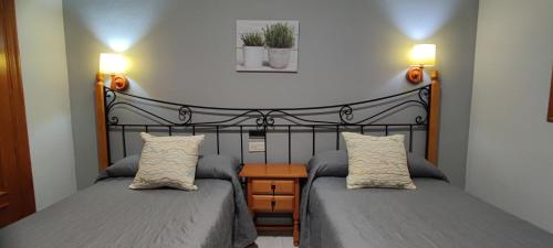 a bedroom with two beds and two lamps on the wall at Apartamentos Lausan in Gavín