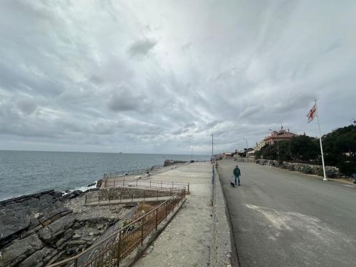 a person walking down a road next to the ocean at MaMi a 2 passi dal mare in Genoa