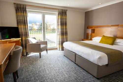 a hotel room with a bed and a balcony at Dale Hill Hotel in Ticehurst