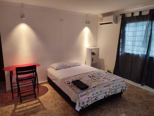 1 dormitorio con cama y mesa roja en Casa Aluna, en Barranquilla