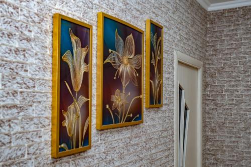 three paintings of flowers are hanging on a wall at Qafqaz Milan Villa With Outdoor Heated Pool in Gabala