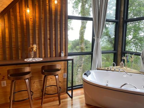 a bathroom with a tub and two stools next to a window at Aslaug Chalé in Urubici