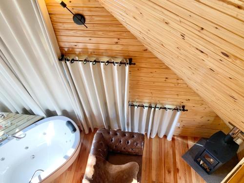 a bathroom with a tub and a wooden ceiling at Aslaug Chalé in Urubici