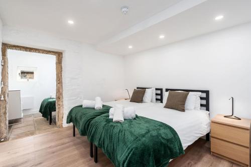 two beds in a bedroom with white walls and wood floors at Dovedale Manor 8 Bedrooms in Tissington