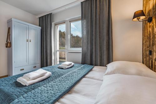 a bedroom with two towels on a bed with a window at Willa Anna Maria in Szczawnica