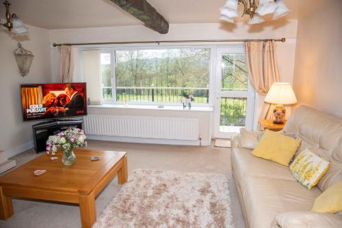 a living room with a white couch and a large window at Tilly Cottage - overlooking Pendle Hill in Barrowford
