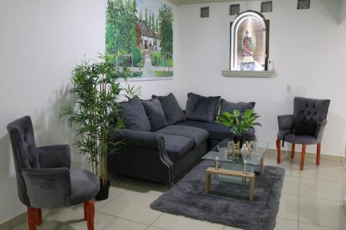 a living room with a blue couch and two chairs at Casa en el centro Calvillo con terraza y mirador in Calvillo
