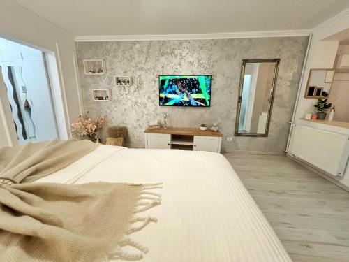 a bedroom with a white bed and a tv on the wall at Studio 118 - A luxury place,Self Check-in ,10 min from City Center in Timişoara