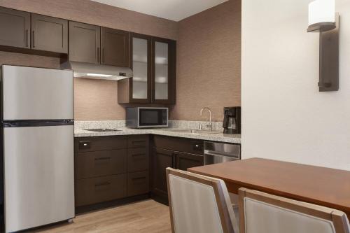 a kitchen with a white refrigerator and a wooden table at Residence Inn San Jose South/Morgan Hill in Morgan Hill
