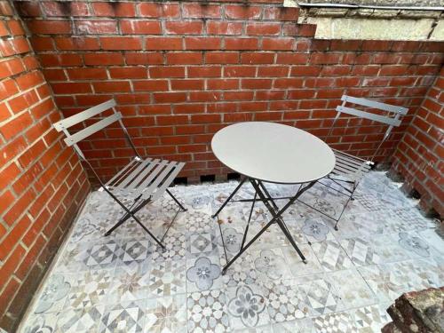 two chairs and a table in front of a brick wall at DAUDREGNIES 3 in Valenciennes