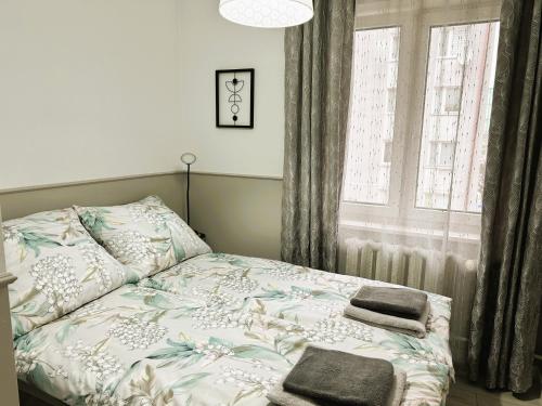 ein Bett mit zwei Handtüchern neben einem Fenster in der Unterkunft Apartament Ełk Centrum II in Lyck