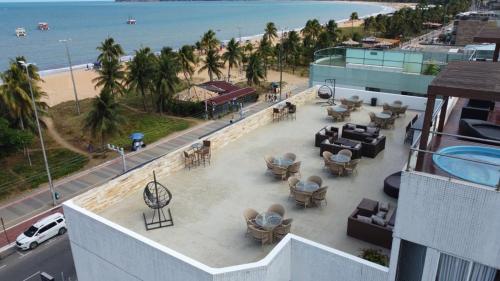 a view of a patio with tables and chairs and the beach at Imperial Tambau By Loui in João Pessoa