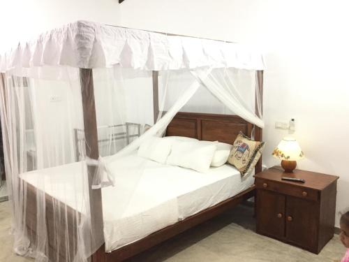 a bedroom with a canopy bed with white sheets and pillows at Tropical Villa in Galle