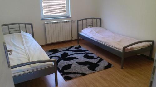 two twin beds in a room with a rug at Apartments Foco in Sarajevo