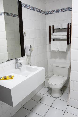 a white bathroom with a sink and a toilet at Hotel Cuenca in Cuenca
