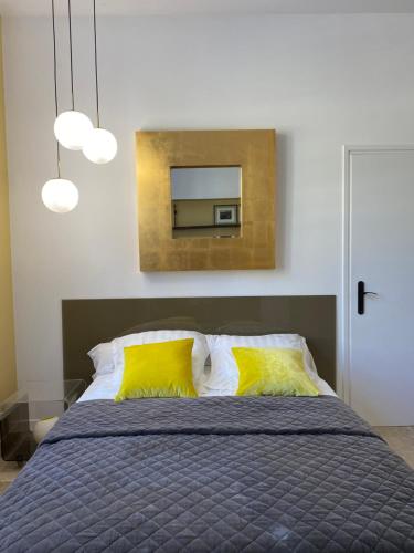 1 dormitorio con cama con almohadas amarillas y espejo en Le KLIMT, en Écully