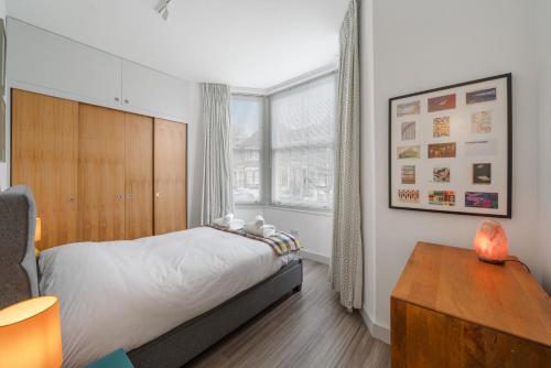 sypialnia z łóżkiem, biurkiem i oknem w obiekcie Ickburgh Road Guesthouse w Londynie